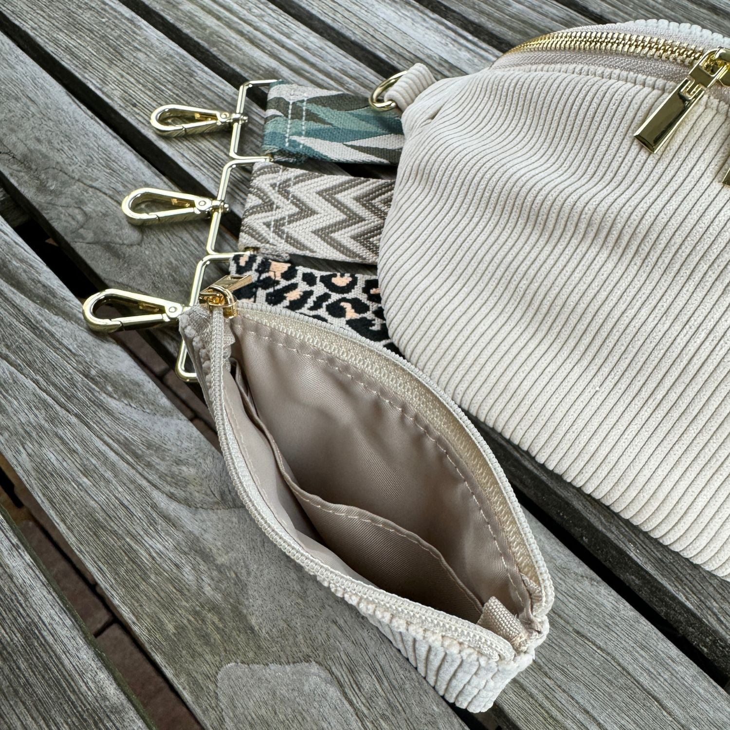 Cord bauchtasche und cord Etui präsentiert mit drei Taschengurten auf Holztisch. Die Verschlussfarbe ist gold.