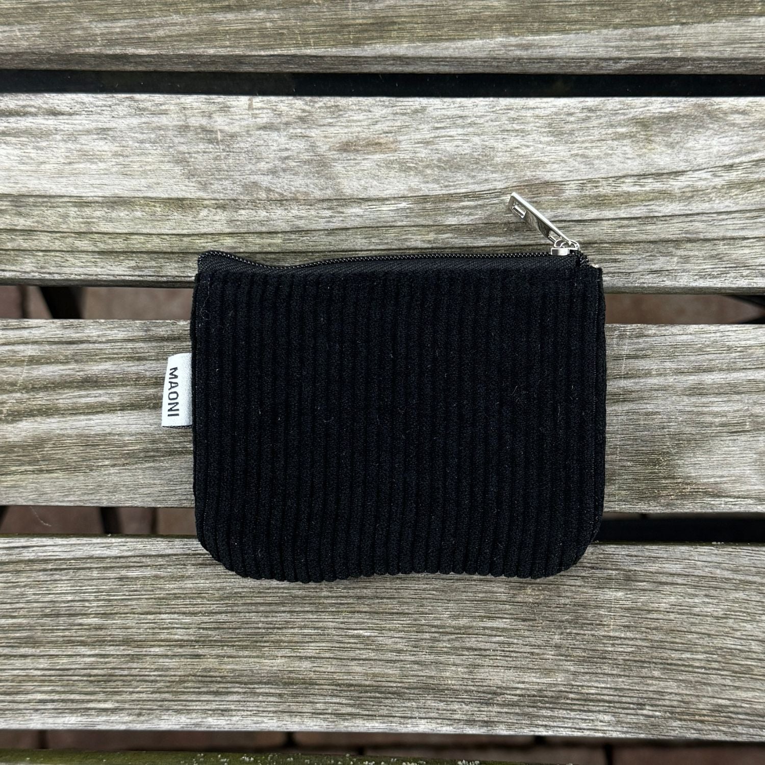 Schwarzes Cord-Etui mit silbernem Reißverschluss, auf einem rustikalen Holztisch präsentiert – modern und funktional.