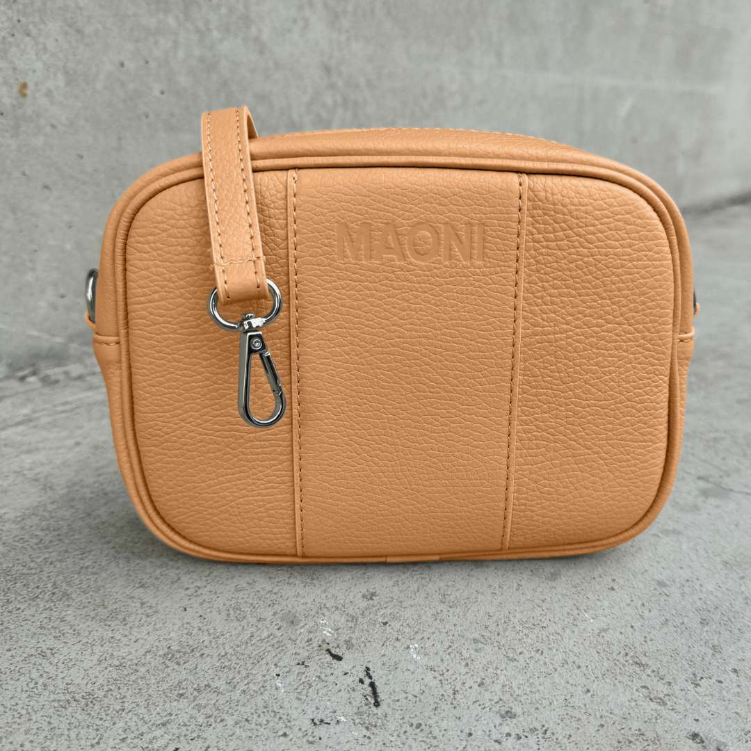 Die Handtasche in Cognac mit gleichfarbigem Ledergurt – ein minimalistisches Design mit klassischem Verschluss in silber.