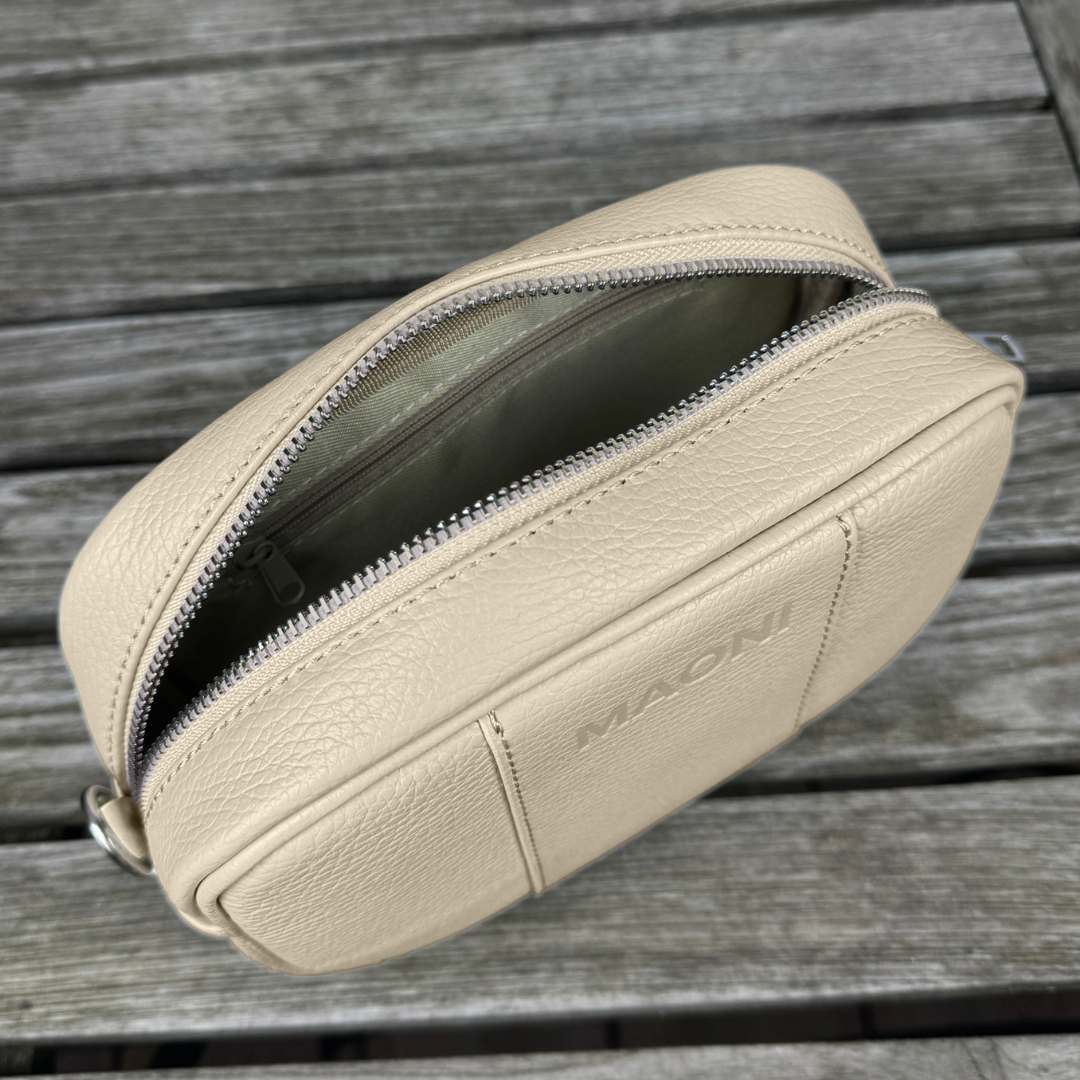 Innenansicht der taupen MAONI Tasche: Offene Handtasche mit praktischem Reißverschlussfach und Einsteckfach, präsentiert auf einem Tisch.