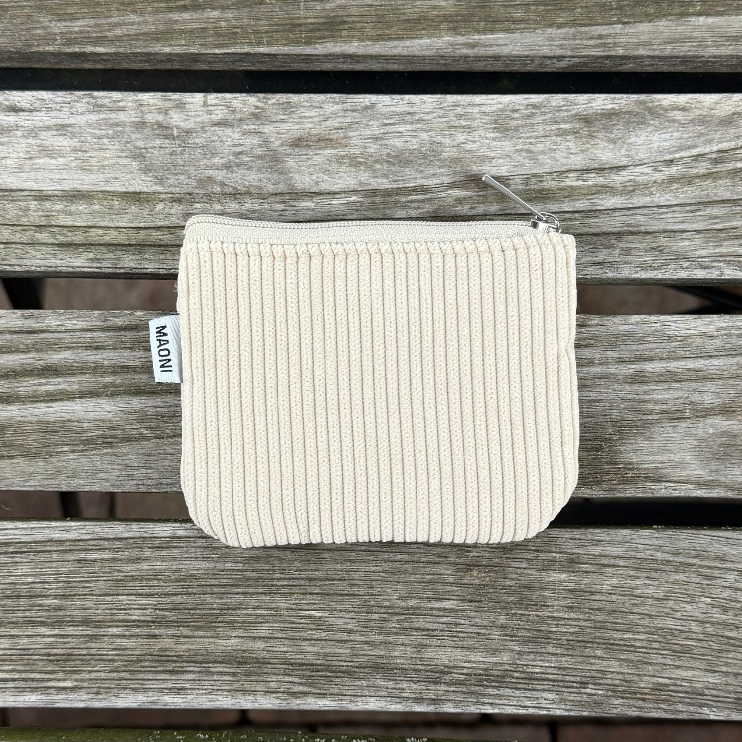 Beiges Cord-Etui mit silbernem Reißverschluss, elegant auf einem Holztisch arrangiert – ideal für den Alltag.
