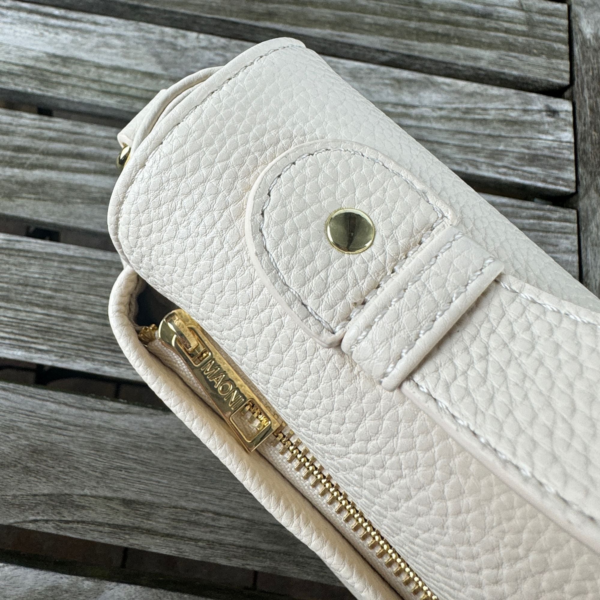 Aus Vogelperspektive: beige halfmoon Tasche. Goldfarbener Reißverschlussfach auf der Rückseite sichtbar.