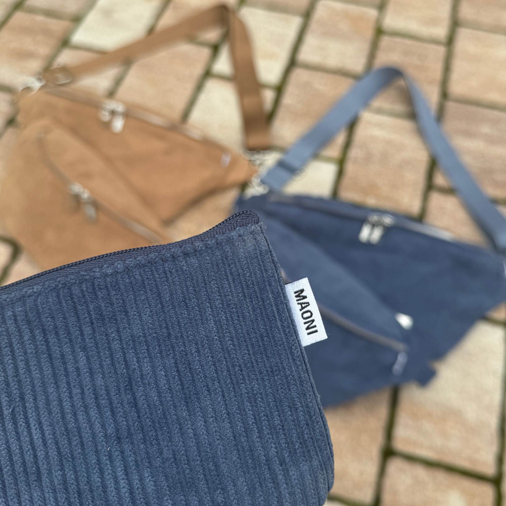 blaues Cord Etui vorne, braune und blaue Cord Bauchtasche im Hintergrund