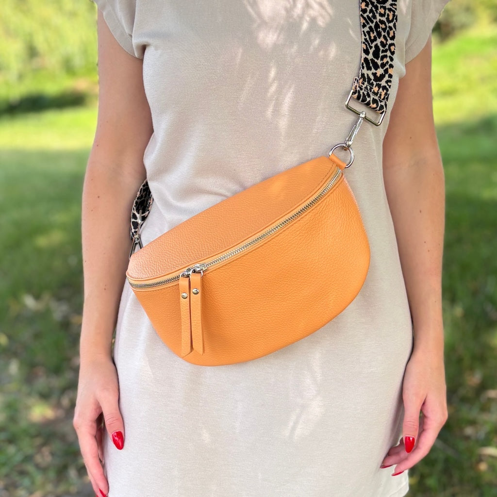 Nahaufnahme der Bauchtasche in Pfirsich mit breitem Leoparden Gurt – farbenfroher Sommerlook, getragen im Alltag