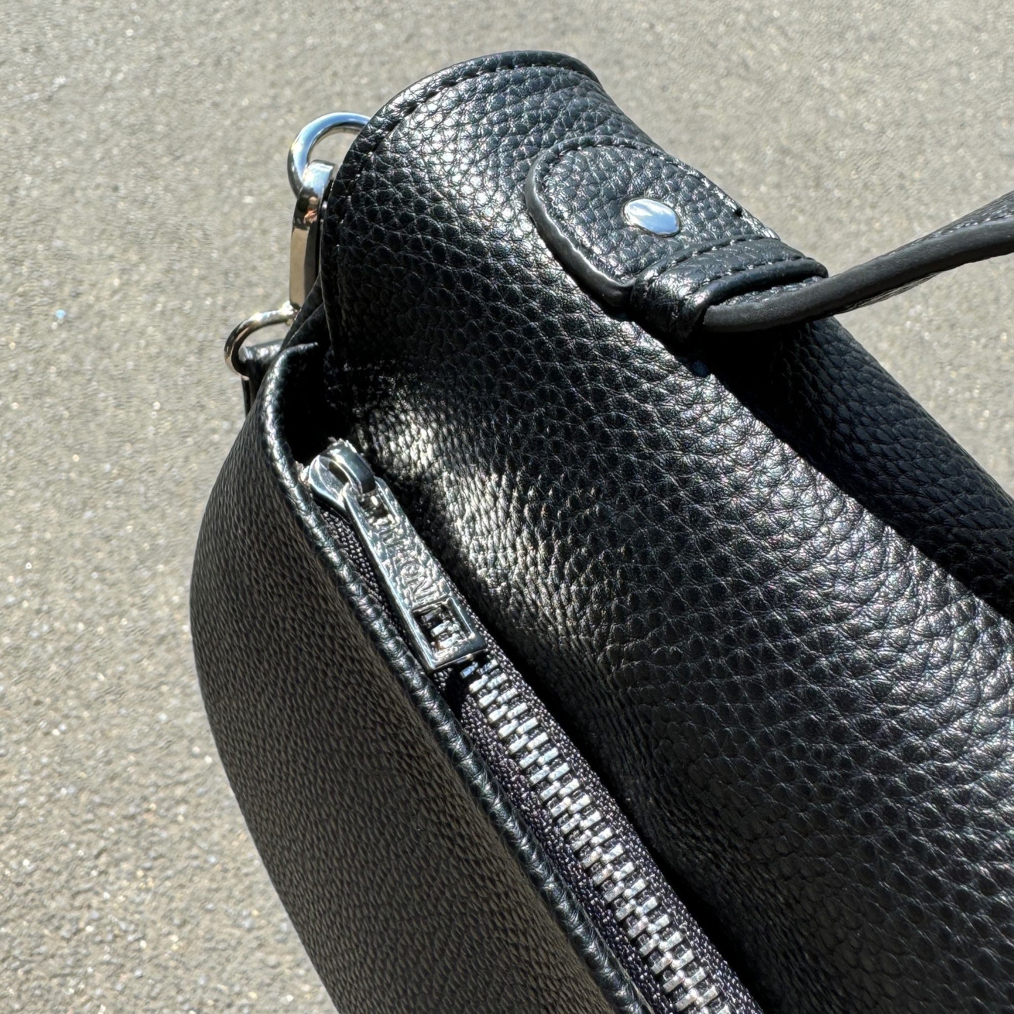 Nahaufnahme der schwarzen Halfmoon-Tasche, Reißverschluss auf der Rückseite deutlich sichtbar.