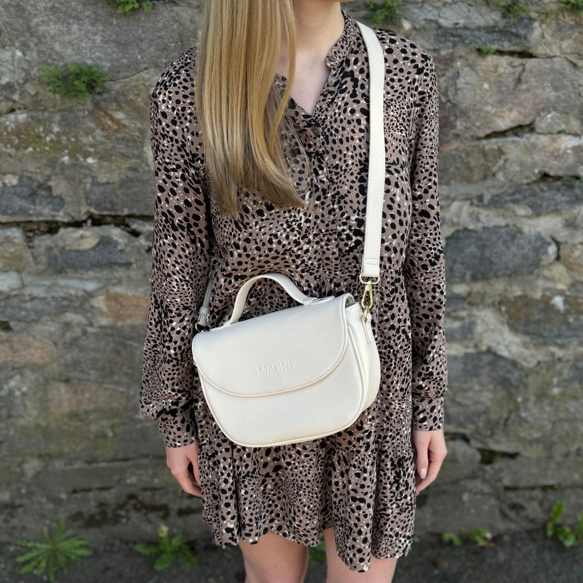 Beige Halfmoon Tasche getragen von junger Frau mit blonden Haaren.
