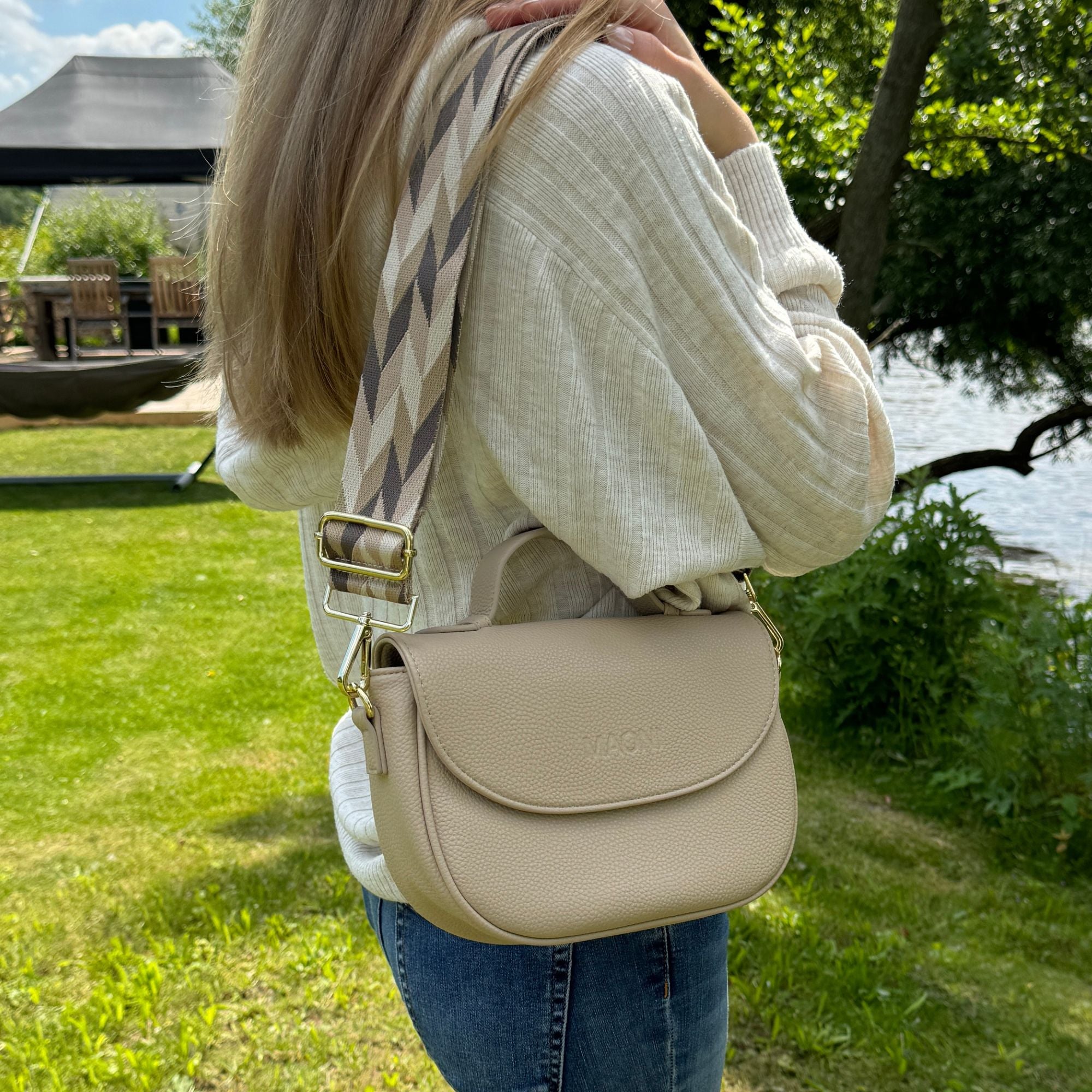 Seitenansicht: Frau trägt taupefarbene Halfmoon-Bag am Fluss.