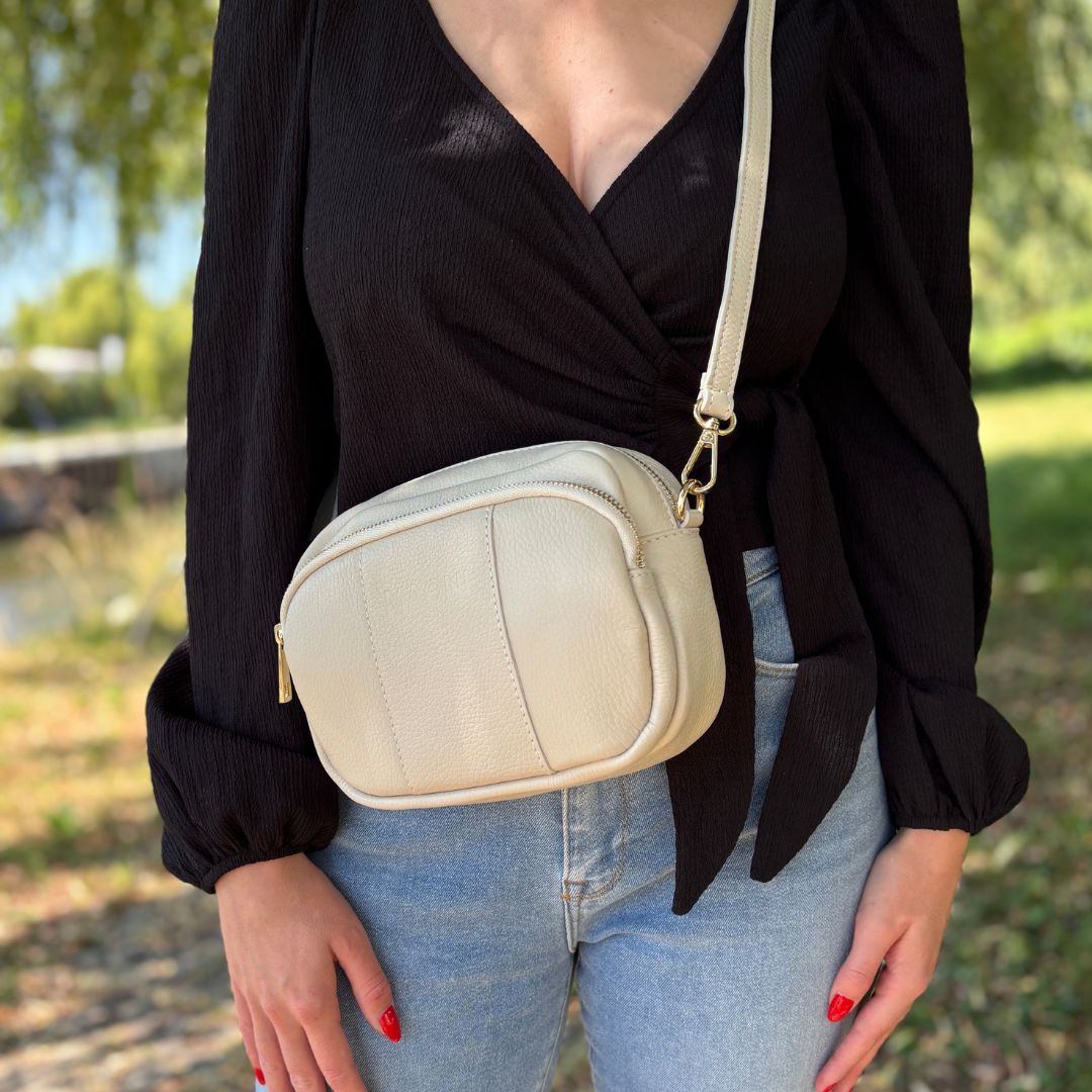 Beigefarbene Crossbody-Tasche, getragen von junger Frau im schicken Alltagslook