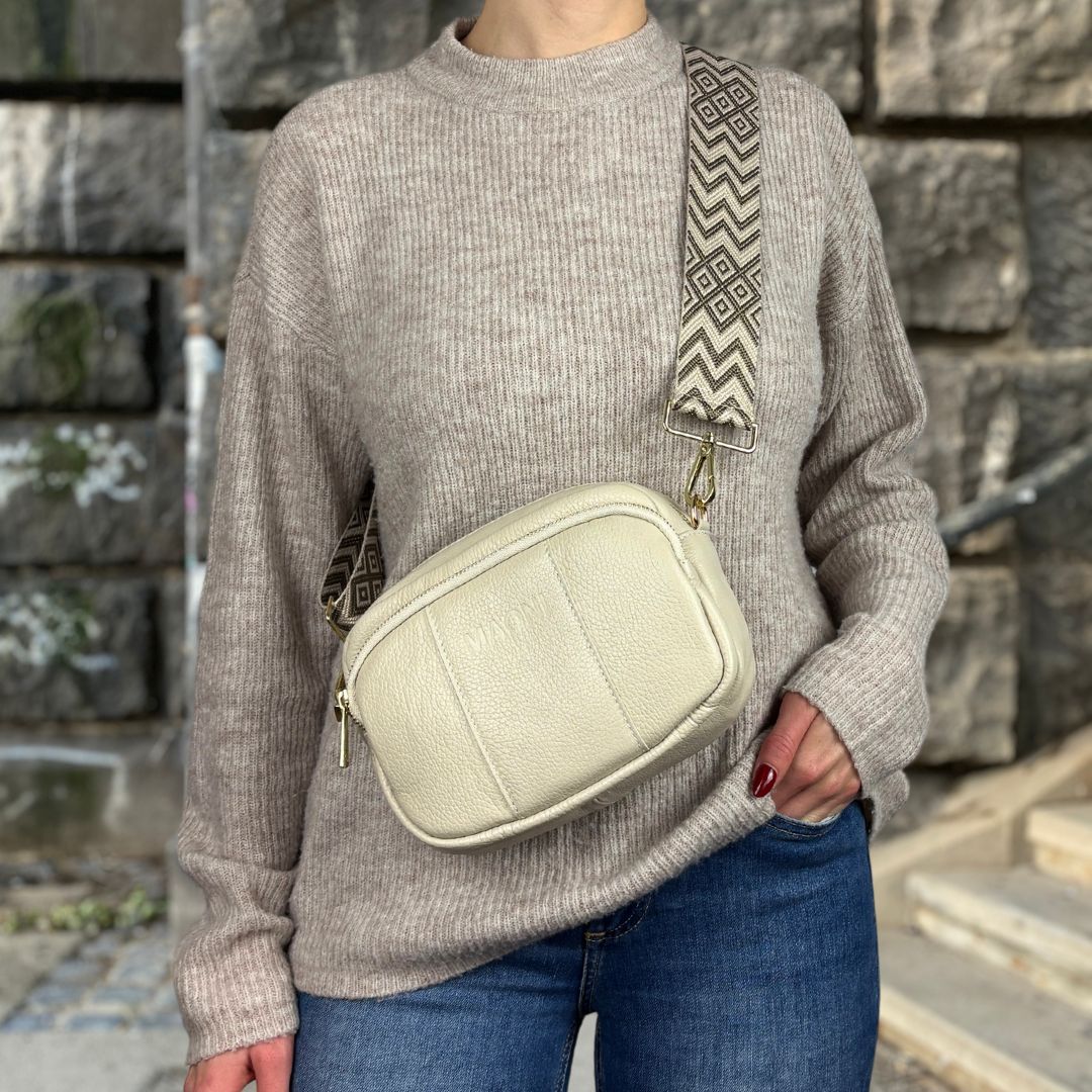 Crossbody Tasche aus Leder mit goldfarbenem Verschluss getragen von Frau mit gezacktem Wechselgurt