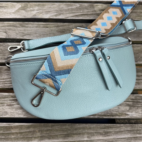 Set in Hellblau: MAONI Bauchtasche mit zwei Gurten auf rustikalem Holztisch inszeniert